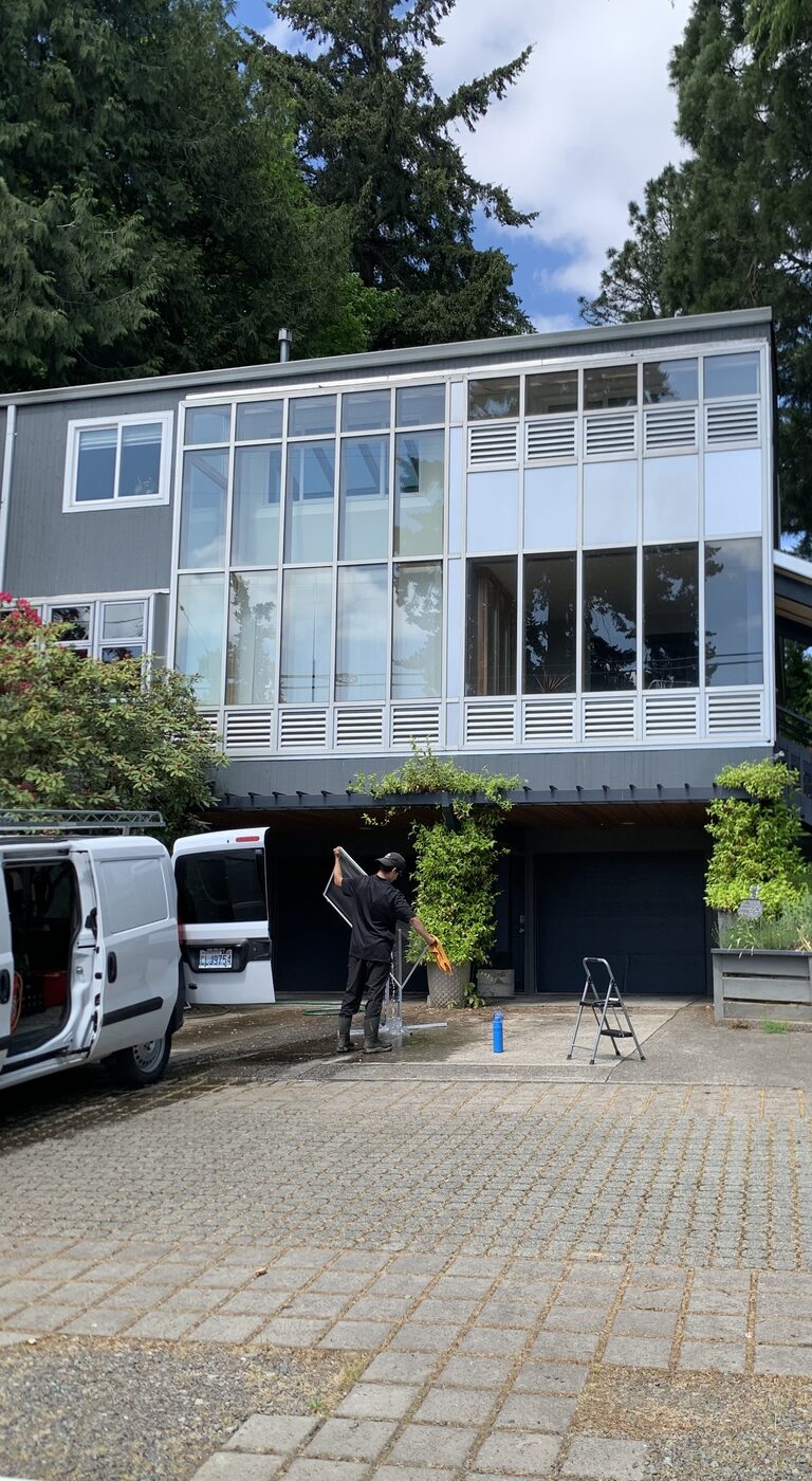 Carlos Montes cleaning windows on a large modern home